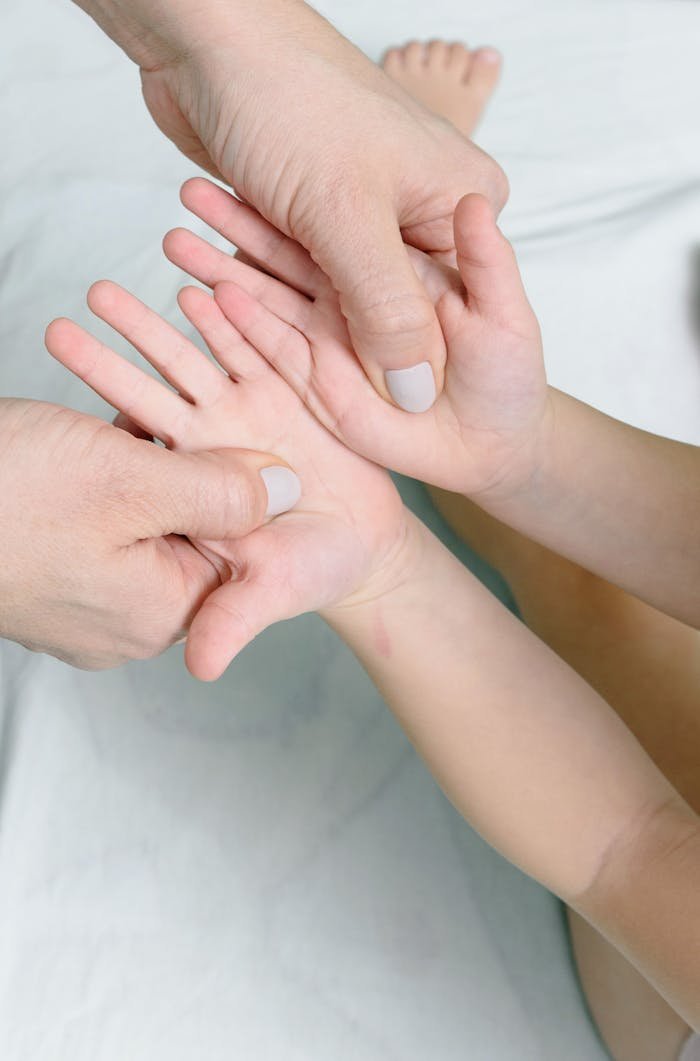 Close-up of an adult giving a gentle massage to a childs hand.